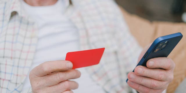 Man holds credit card and his phone