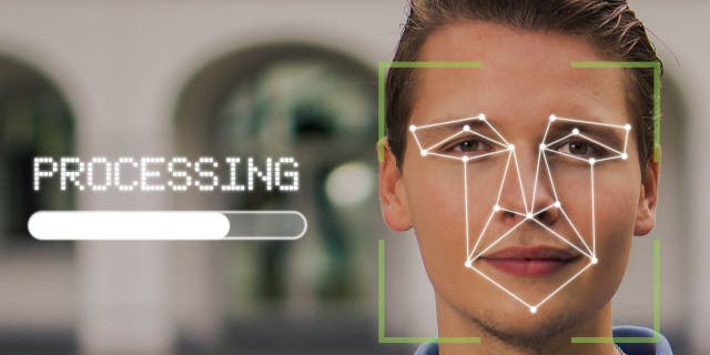 Photo of a person with their face being mapped out by facial recognition software.