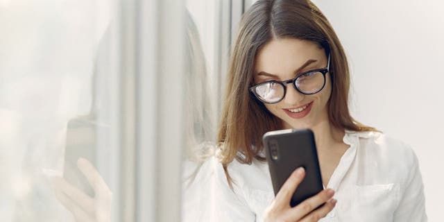 La mujer sonríe en el teléfono inteligente Android