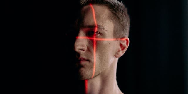 A photo of a man's face being scanned with two red lines.