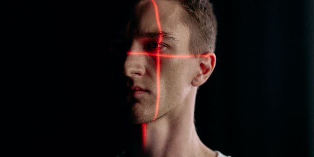 Photo of a man's face being scanned by two red lines.