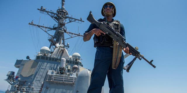 Un marinero de la Marina de los EE. UU. en cubierta con un rifle