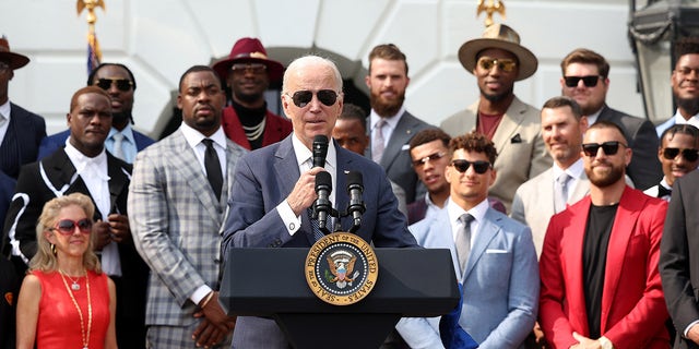 Joe Biden speaks with Harrison Butker in background