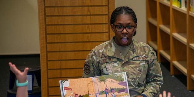 camouflaged volunteer reads book to children during read with pride event