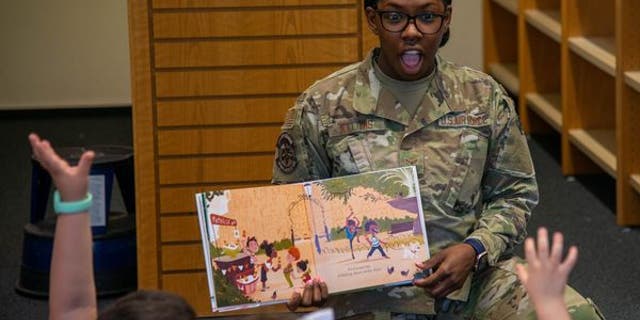 camouflaged volunteer reads book to children during read with pride event