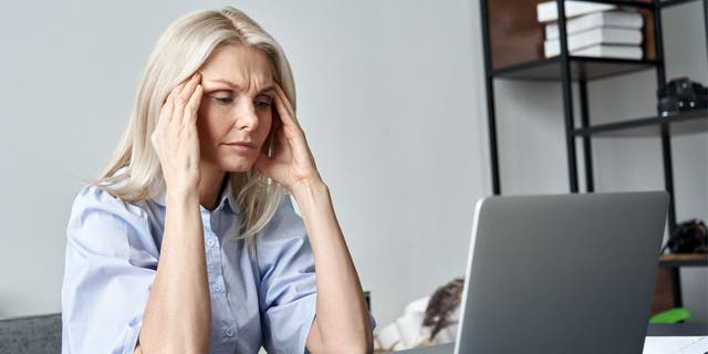 A photo of a woman stressed on her laptop