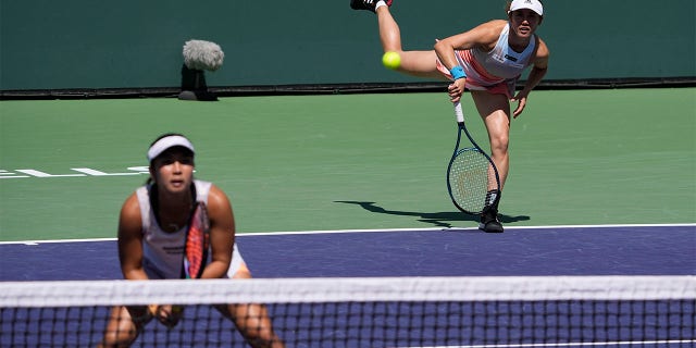 Miyu Kato serves behind Aldila Sutjiadi