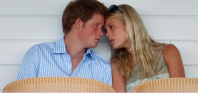 Prince Harry in a blue and white striped shirt leaning againsyt Chelsy Davy in a green and white top