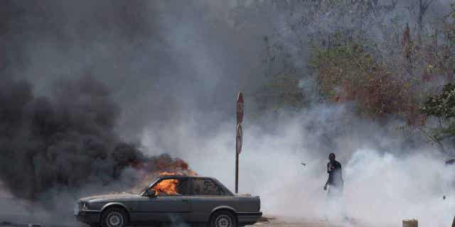 A demonstrator walks through smoke of tear gas