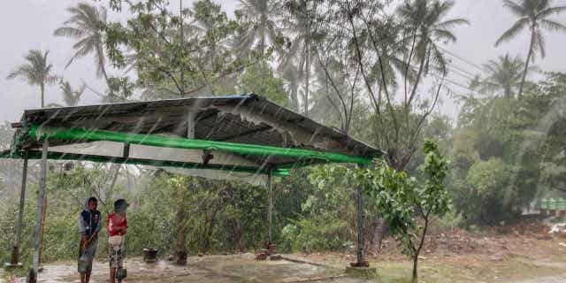 Two children stand under a roadside shelter 