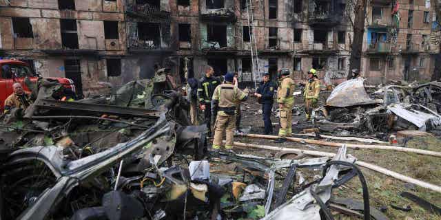 Emergency workers inspect a damaged apartment