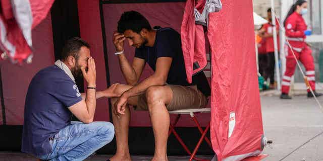 Survivors of a shipwreck react outside a warehouse at the port