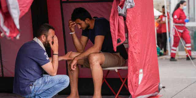 Survivors of a shipwreck react outside a warehouse at the port