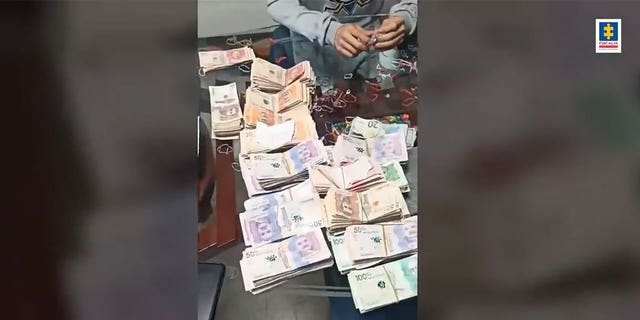 Montones de dinero en efectivo sobre una mesa incautados en un allanamiento en Colombia.