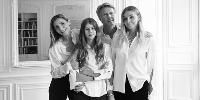A black and white photo of Prince Emanuele Filiberto with his wife and two daughters all wearing white shirts and dark pants