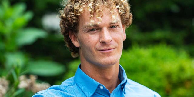 Daniel Penny, wearing a button down blue shirt in a park.