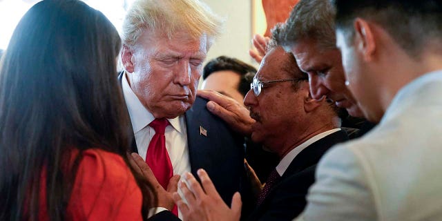 Donald Trump prays with supporters at Versailles restaurant