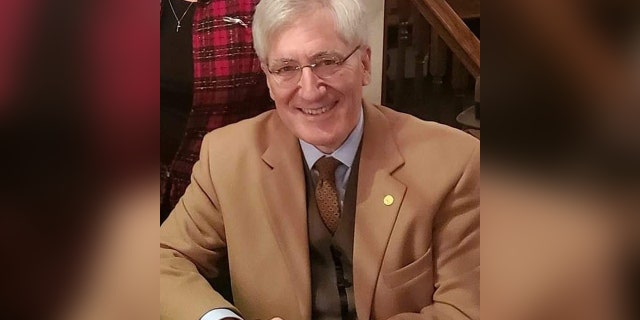 Dr. Robert P. George smiling in a tan suit