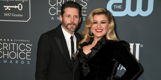 Kelly Clarkson smiles on the red carpet at the Critics' Choice Awards with husband Brandon Blackstock