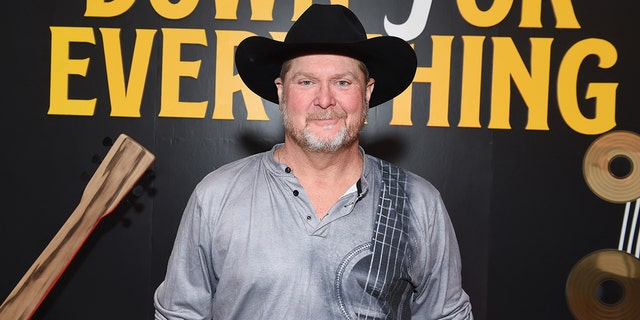 Tracy Lawrence smiles wearing a black cowboy hat ahead of the CMAs