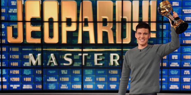 A photo of James Holzhauer holding a trophy on the "Jeopardy!" set