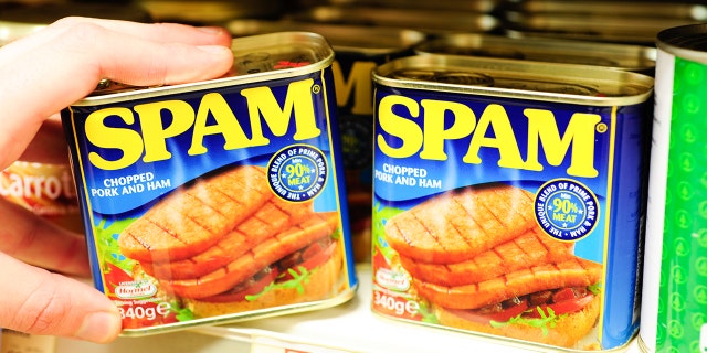 Can of spam on grocery shelf being held by person