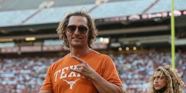 Matthew McConaughey wearing a Texas longhorns t-shirt and flashing the longhorns hand gesture