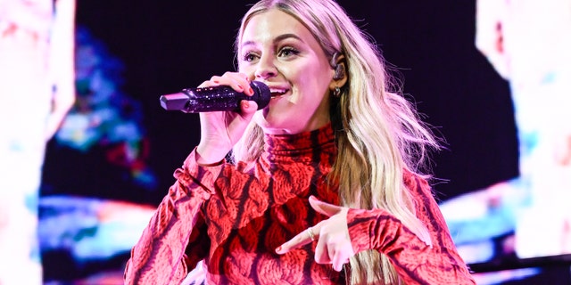 Kelsea Ballerini in a red patterned top singing into the microphone