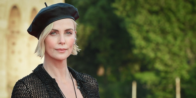 Charlize Theron in a black beret and black dress.