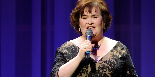 Susan Boyle in an off-shoulder gown sings into the microphone in Las Vegas