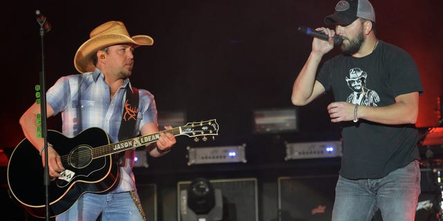 Jason Aldean performing onstage with Tyler Farr