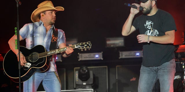 Jason Aldean performing onstage with Tyler Farr