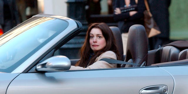 A photo of Anne Hathaway grimacing behind the wheel of a car.