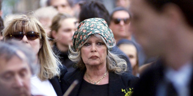 Brigitte Bardot wearing a black dress and a green scarf on her hair