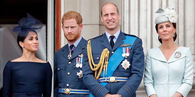 Meghan Markle, Prince Harry, Prince William and Kate Middleton in regal royal clothing standing on the balcony of Buckingham palace