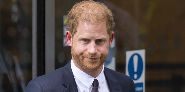 A close-up of Prince Harry looking stern in a dark suit