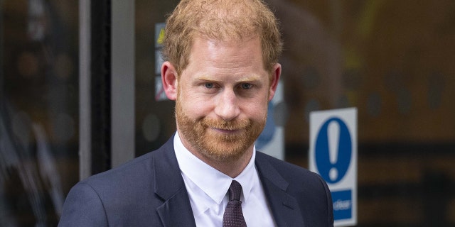 A close-up of Prince Harry looking stern in a dark suit