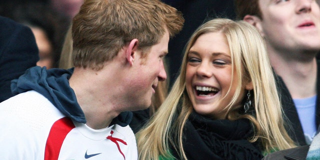 Prince Harry in a sports uniform laughing with Chelsy Davy wearing a scarf