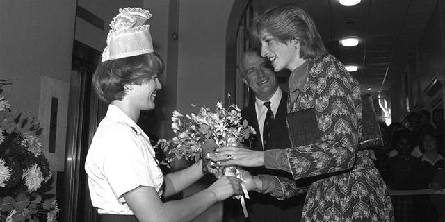 A black and white photo of Princess Diana receiving a bouquet of flowers from a nurse