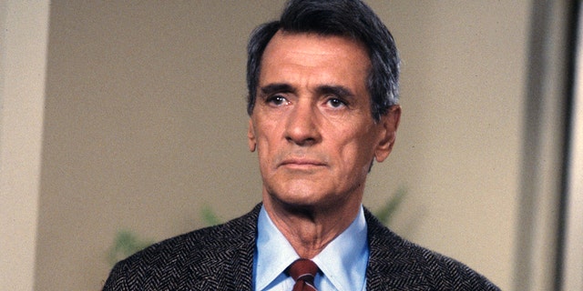 A close-up of Rock Hudson wearing a suit on the set of Dynasty