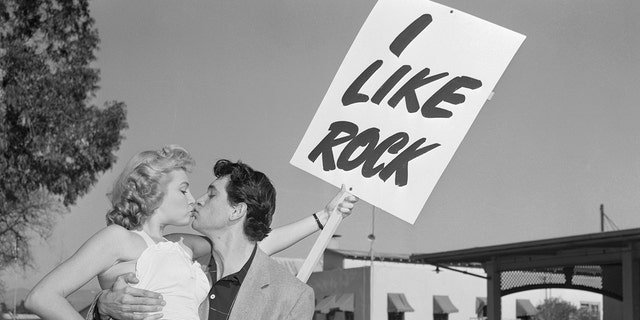 Rock Hudson gets a kiss from a woman holding an I Like Rock sign