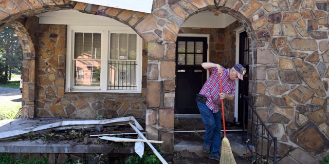 A man sweeps debris off of his front porch in North Little Rock, Arkansas