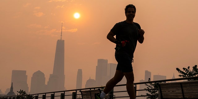 A man jogs through the Liberty State Park while the smoke from Canada wildfires covers the Manhattan borough