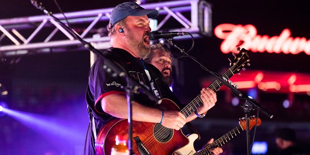 John Driskell Hopkins strums the guitar and sings on stage during Zac Brown Band concert