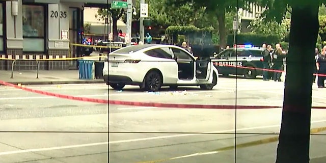 Crime scene tape in front of white Tesla with it's passenger door open.