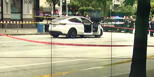 Crime scene tape in front of white Tesla with it's passenger door open.