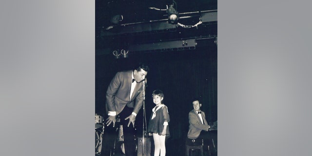 Louis Prima bending down while looking adoringly at his daughter Lena Prima