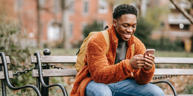 Male Apple iPhone user smiles as he types