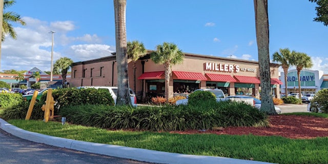 A single story restaurant flanked by palm trees.