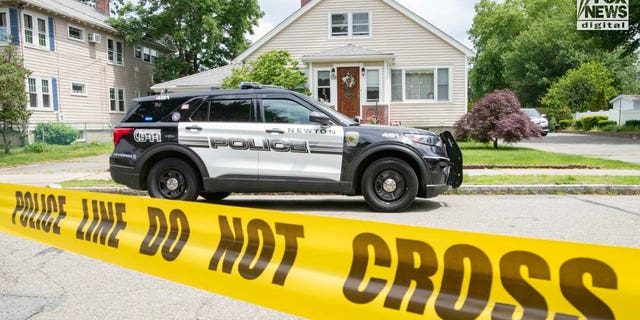 Police officers gather outside of the home where a triple homicide occurred in Newton, Massachusetts